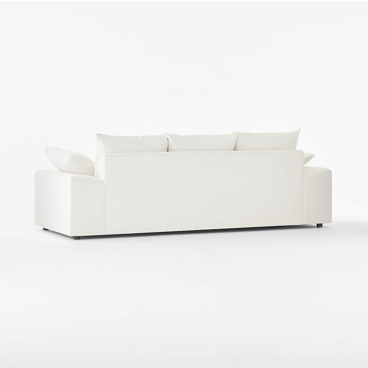 The Algora 100" White Performance Fabric Sleeper Sofa showcases a minimalist design with a modern aesthetic when viewed from the back. It boasts clean lines, a solid base, and includes four matching cushions. The plain background enhances the sofa's simplicity and elegant appearance.