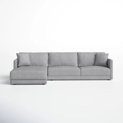 The Astra 2-Piece Upholstered Sectional is a contemporary gray sofa with clean lines and a left-side chaise, accompanied by matching cushions, all set against a plain white backdrop.