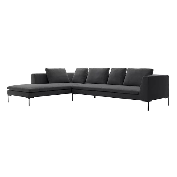 The Charles Left Arm Sectional Sofa by B&B Italia is a contemporary dark gray piece with a chaise on the left side, characterized by sleek lines and supported by slender black legs. It includes five back cushions and is displayed against a plain white background.