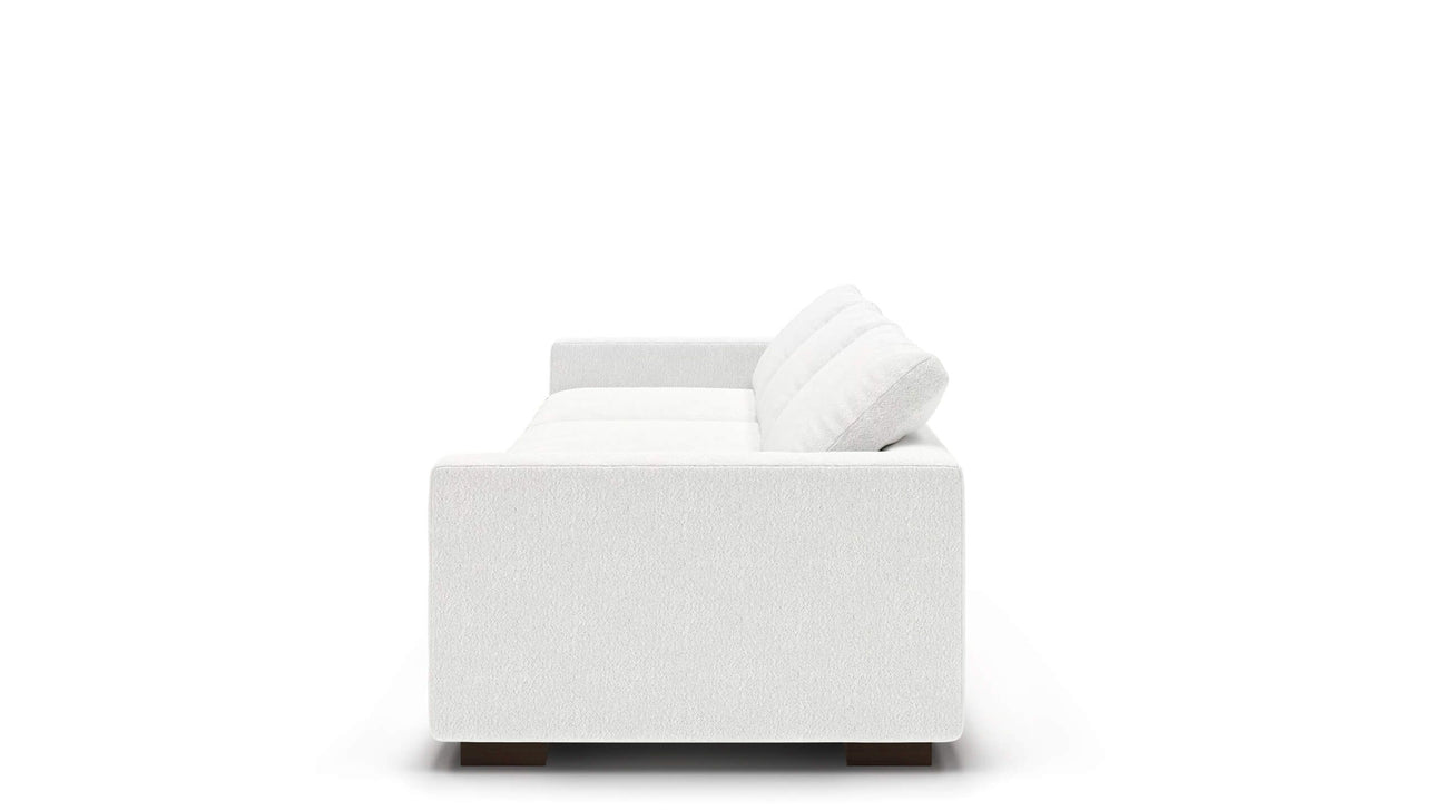 Side view of the Like Butter 106" Sofa in Enzo/Cream Leather with two back cushions against a plain white background. The sofa features a boxy shape and dark wooden legs.