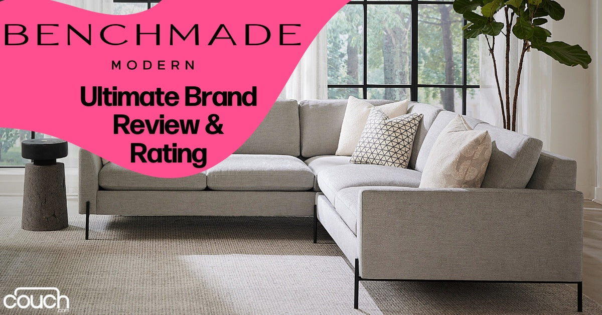 A modern gray sectional sofa in a spacious, well-lit living room with large windows and a potted plant. The wall features a review banner for Benchmade Modern, stating "Ultimate Brand Review & Rating.