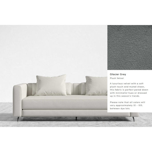 The Berlin Sleeper Sofa, upholstered in glacier grey plush velvet, includes two large and two small matching pillows, all showcased against a plain backdrop. The fabric is noted for its soft texture and muted sheen. Be aware that color variations of 10-15% may occur between dye lots.