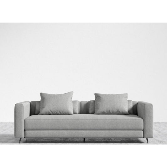 Placed against a plain white wall is the Berlin Sleeper Sofa, a modern piece with clean lines. It comes with two matching square cushions and stands on slim metal legs, resting on a light gray floor.