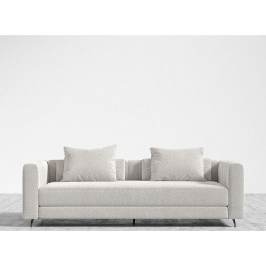 A minimalist living room showcases the Berlin Sleeper Sofa in a light gray hue, complete with two matching cushions, set against a plain white wall. The sofa boasts a modern design with straight lines and a luxuriously soft fabric texture. The floor is also light gray, perfectly complementing the sofa's aesthetic.