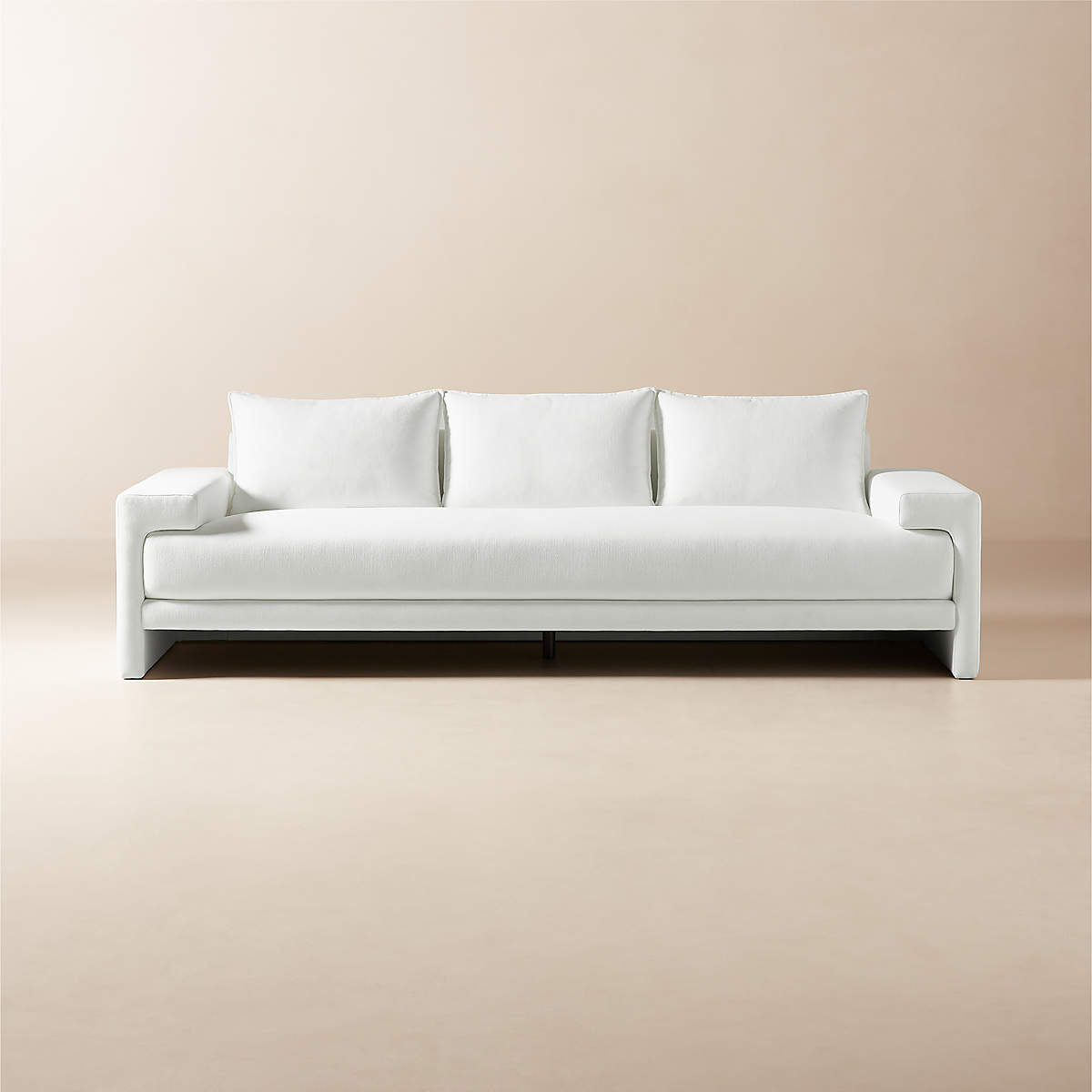 A sleek and modern Camden 101" White Performance Fabric Sofa against a beige background, boasting a minimalist design with three back cushions, wide armrests, and a low-profile seat.