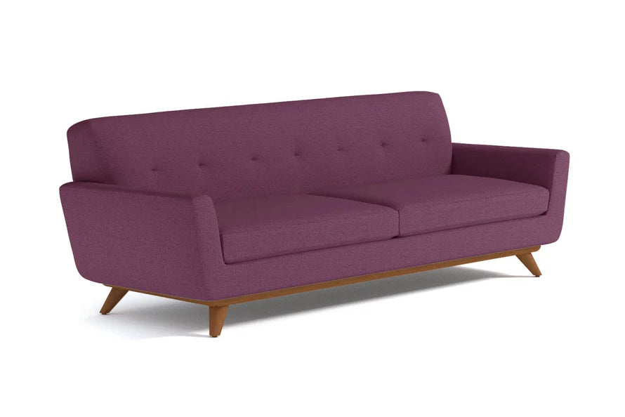 A Carson Sofa in purple, featuring wooden legs and a button-tufted backrest, viewed from the front at an angle.