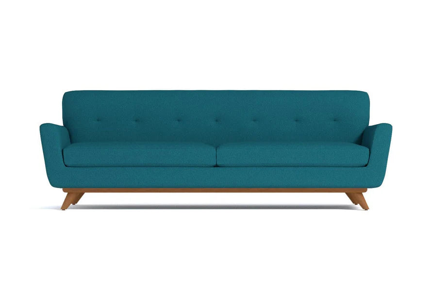 The Carson Sofa is a teal, mid-century modern piece featuring a tufted backrest and two seat cushions, elegantly set on wooden legs against a white background.