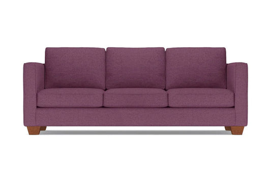 The Catalina Sofa, a plum-colored three-seater with wide armrests and wooden legs, is set against a plain white background. It features three plush seat and back cushions.