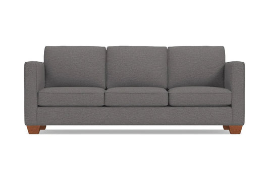 The Catalina Sofa is a gray, three-seater piece with a minimalist design and wooden legs. It features straight arms and three back cushions, set against a plain white background.