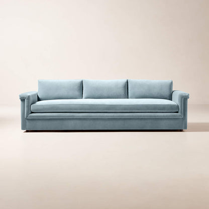 The Ceva 103" Light Blue Performance Velvet Sofa showcases a sleek and contemporary style with its minimalist design, three cushions, and low arms. It is set against a plain, light beige background to emphasize its modern appeal.