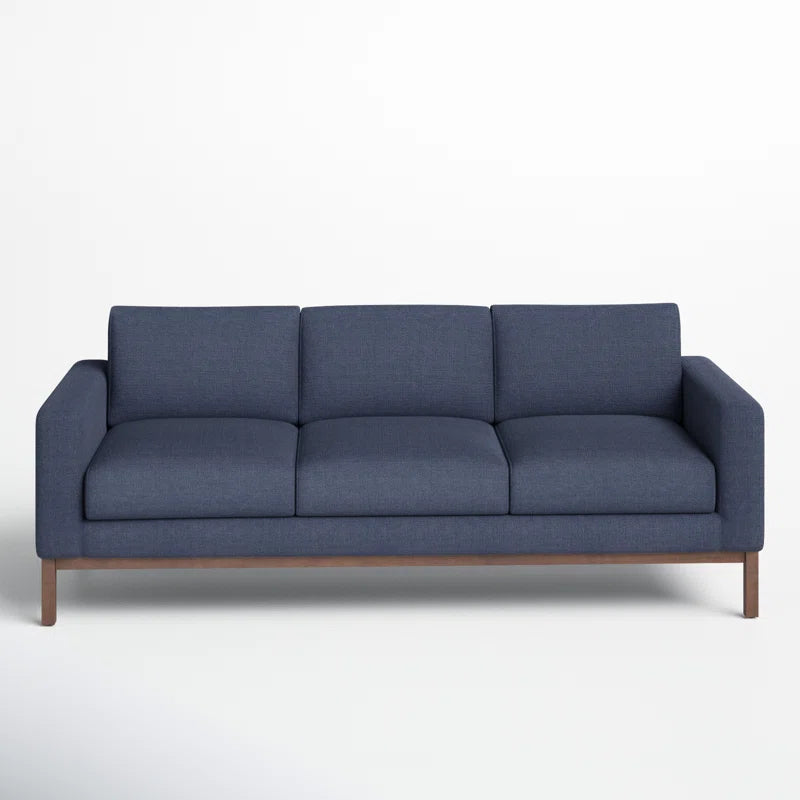 The Clayton 83.1" Upholstered Sofa is a modern, minimalist piece featuring a blue upholstery with three cushions and a wooden base, set against a plain white background. It has straight armrests and boasts a sleek design, making it both stylish and comfortable for seating.