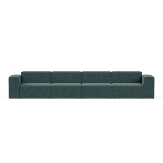 The Four-Seater Form Sectional is a spacious dark green modular sofa with six sections, featuring armrests on both ends, set against a plain white background and boasting a minimalist and contemporary design.