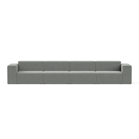 A large, modern Four-Seater Form Sectional in gray is showcased against a plain backdrop. Its minimalist design includes four wide seats and square armrests, offering a sleek and contemporary appearance.