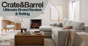 A modern living room features a beige sectional sofa with a blanket draped over the arm, a wooden coffee table with decorative items, a textured rug, a wicker chair, and a floor lamp. The text reads "Crate&Barrel Ultimate Brand Review & Rating." The logo for "The Couch" is in the corner.