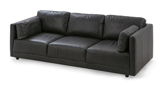 The Domus 93" Leather Sofa is a black leather sofa featuring three cushions, square arms, and two side pillows. Its modern design boasts a sleek, minimalist appearance with low-profile black legs.