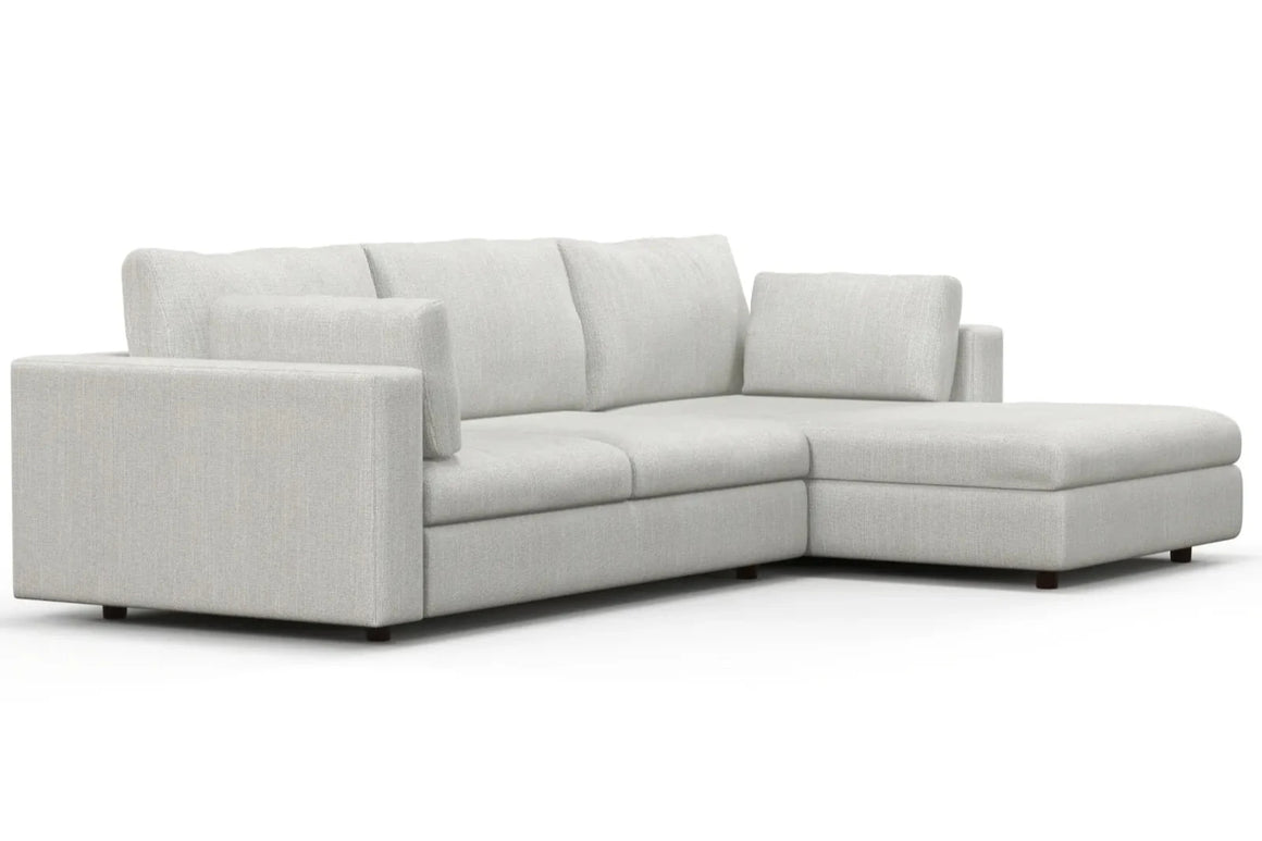 The Daphne Chaise 96" Sofa is a contemporary gray sectional with a right-side chaise lounge. It boasts clean lines and seems to have a textured finish, featuring three back cushions and a low-profile armrest on one side.