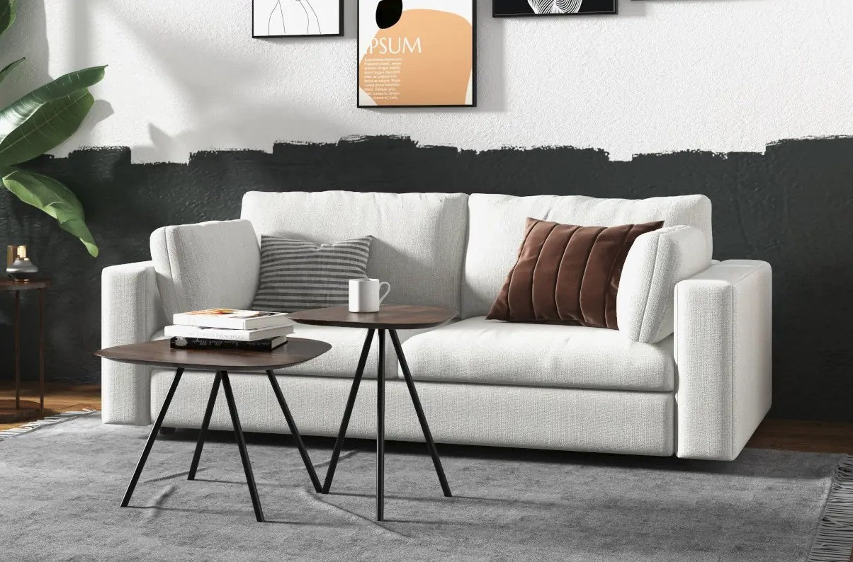 White sofa in front of a black and white wall. Two small tables with books and a coffee cup lay in front. 