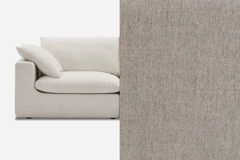 A partial view of a beige sofa with a textured fabric. The image shows the sofa on the left, complete with a cushion, and an enlarged section of the upholstery fabric on the right, highlighting its detailed texture.