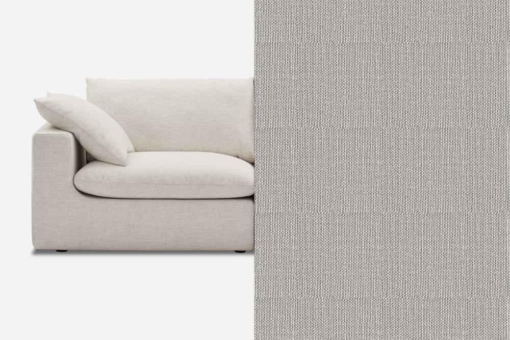 A light gray sofa with a plush cushion is shown on the left, while the right side displays a close-up of the sofa's fabric, highlighting its woven texture. The sofa is positioned against a plain white background.