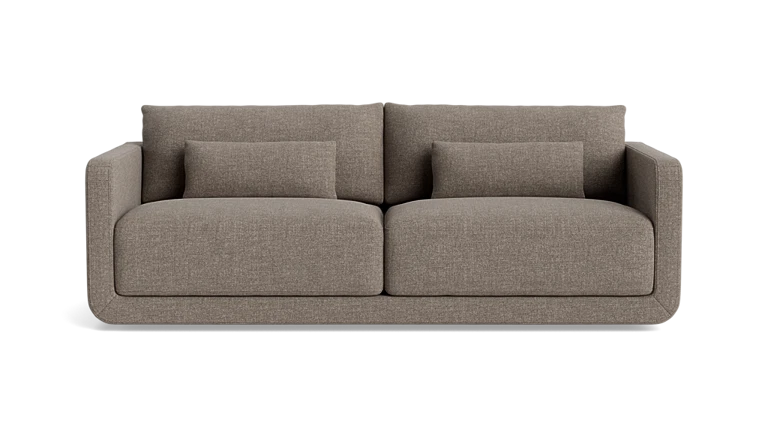 The Eva 85" Sofa is a modern design in brown, featuring two large cushions and two smaller rectangular pillows, set against a plain background.