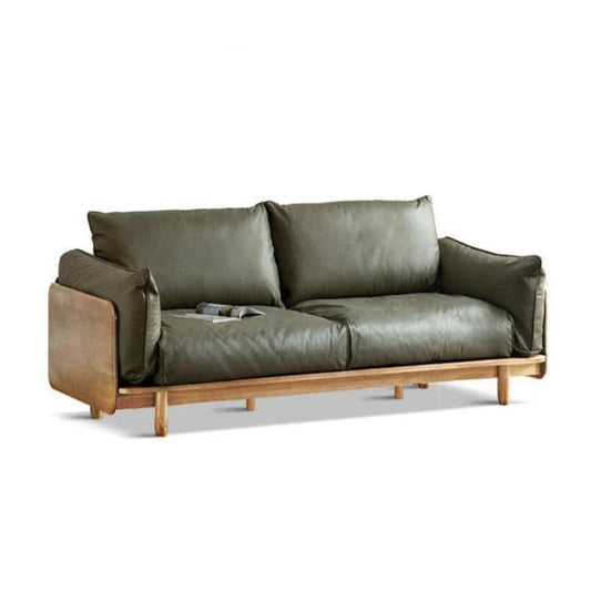 The Elwood 9-Seater Sofa, featuring a contemporary design with luxurious green leather upholstery and a sturdy wooden frame, boasts plush cushions. A magazine rests on one of the cushions, while the sofa is showcased against a simple white backdrop.