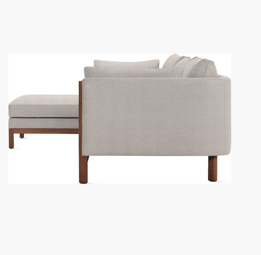 A side view of the Emmy Sectional with light gray cushions and wooden legs, positioned against a white background. The L-shaped design is simple and elegant, highlighting its clean lines and contemporary style.