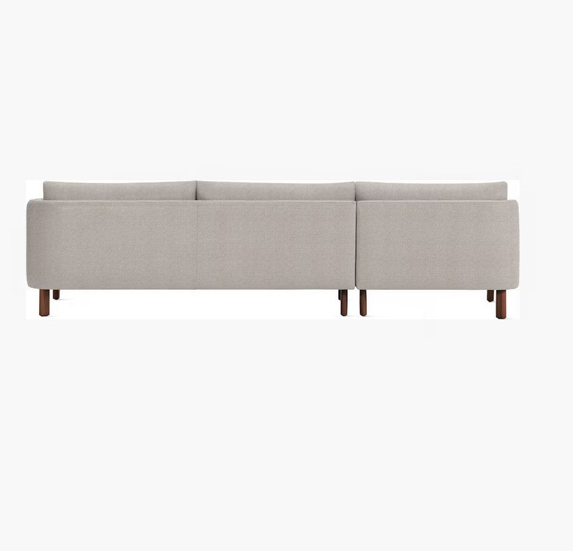 Back view of the Emmy Sectional, a modern, light gray sofa with wooden legs, set against a plain white background. The sofa features a minimalist design with clean lines and a smooth finish.