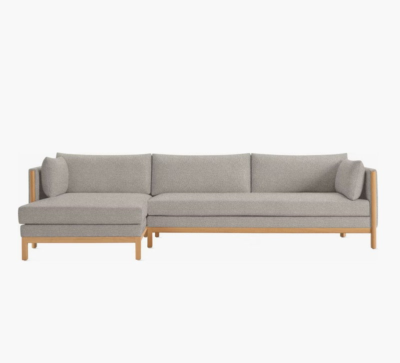 The Emmy Sectional is a stylish, modern sofa in light gray with wooden legs and a left-side chaise. It showcases clean lines and a minimalistic design, perfect for contemporary interiors.