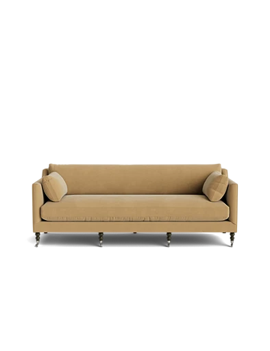 The Fabienne Sofa, upholstered in beige fabric, is accompanied by two matching round pillows and set against a plain black background. It features a straightforward design with wooden legs that offer a timeless and sophisticated appearance.