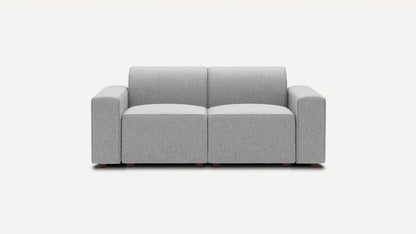 Introducing the Mambo Loveseat, a contemporary gray seating option with a minimalist design. It features two cushioned seats and armrests on both sides, offering a sleek and refined look against a plain white background.