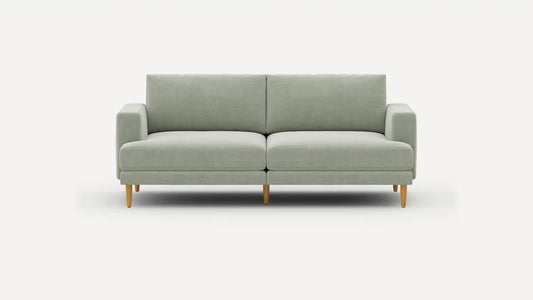 The Ember Mid-Century Modern 75" Sofa is showcased against a plain white background, highlighting its minimalist and contemporary design with a light green color, clean lines, and wooden legs. It includes two seat cushions and two back cushions for added comfort.