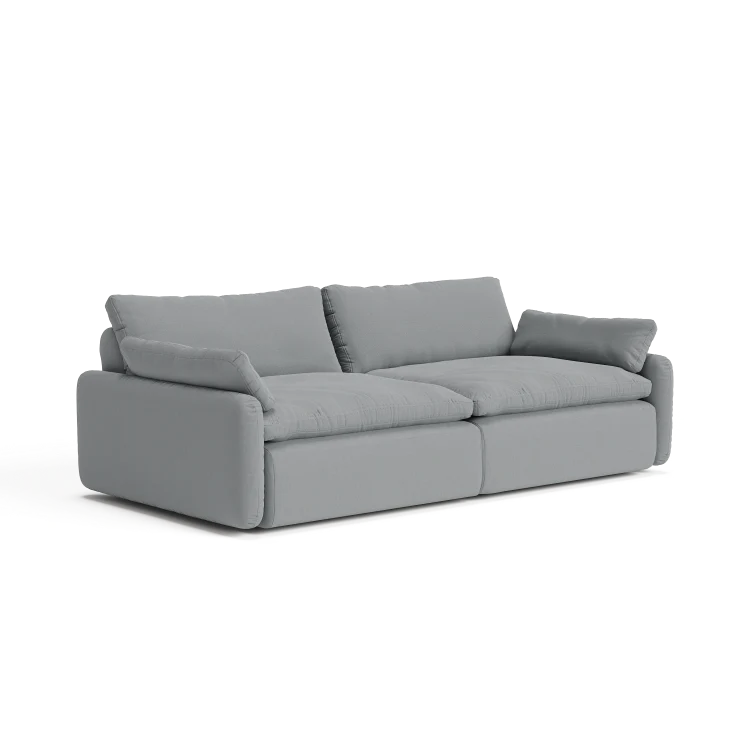 Introducing The Sink Down Sectional: a contemporary gray sofa with plush cushions and two large back pillows, showcasing a minimalist design. This sofa features wide armrests and a low-profile frame, all set against a white backdrop.