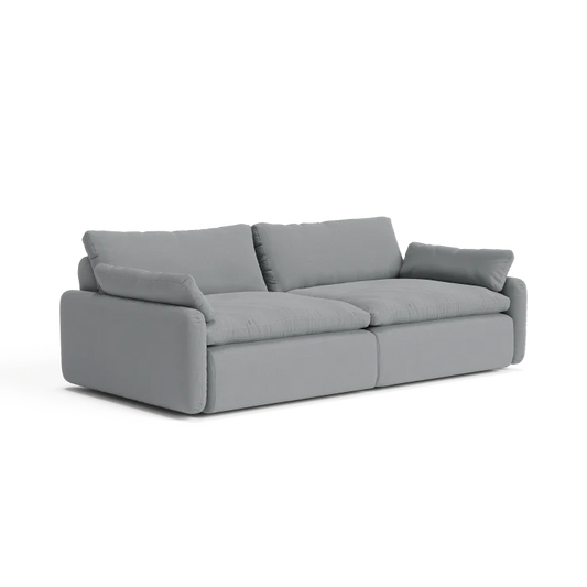 Introducing The Sink Down Sectional: a contemporary gray sofa with plush cushions and two large back pillows, showcasing a minimalist design. This sofa features wide armrests and a low-profile frame, all set against a white backdrop.