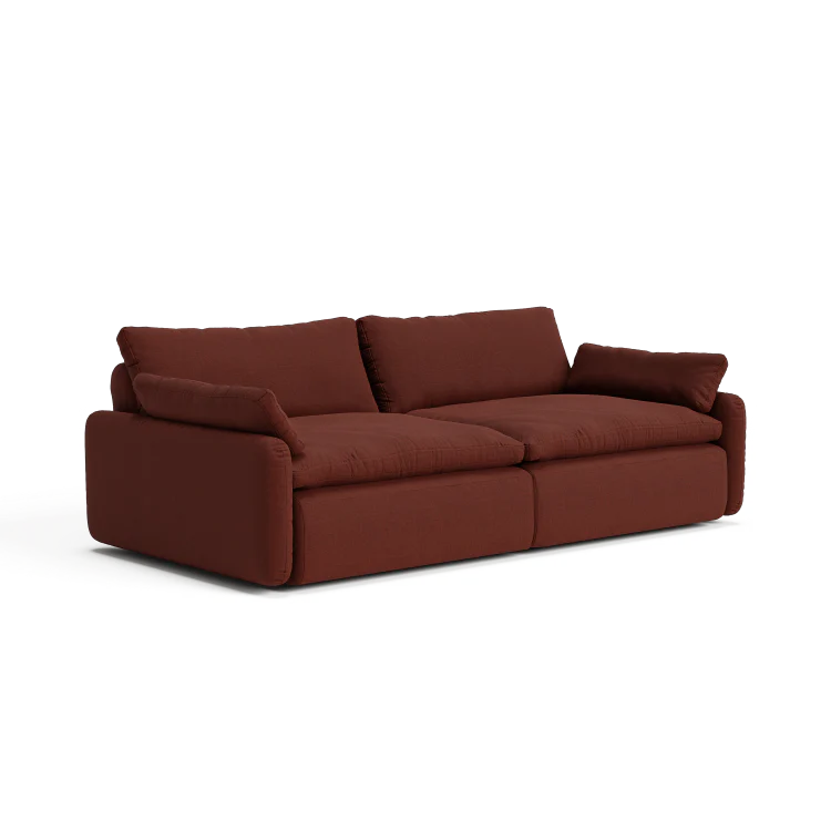 The Sink Down Sectional is a plush sofa in a deep red shade, featuring soft cushions and wide armrests. Its contemporary design and cozy, inviting appearance make it perfect for a modern living room.