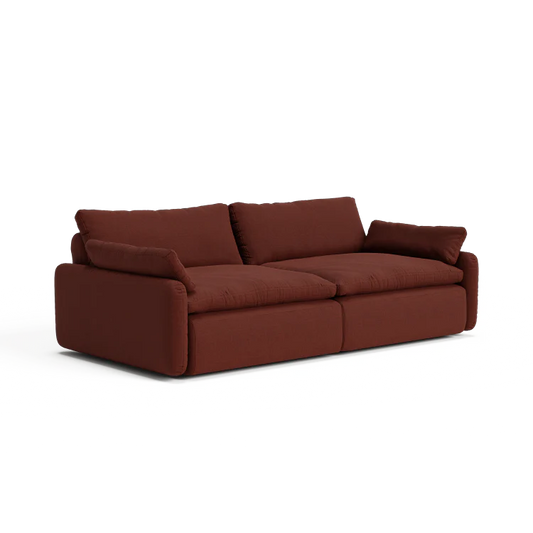 The Sink Down Sectional is a plush sofa in a deep red shade, featuring soft cushions and wide armrests. Its contemporary design and cozy, inviting appearance make it perfect for a modern living room.