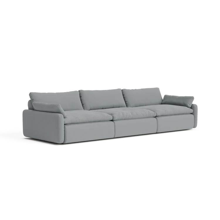 The Sink Down Sectional is a modern sofa in a gray hue, featuring three plush seats and cushioned backrests on a white background. It boasts a minimalist design with clean lines and soft fabric.