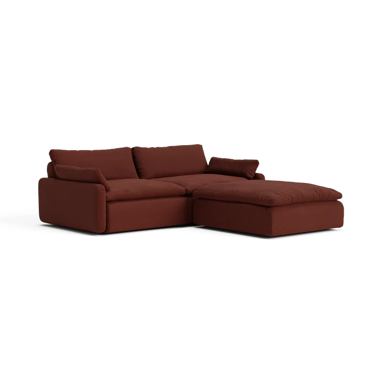 The Sink Down Sectional is a modern, deep burgundy sofa featuring plush cushions and a chaise lounge on the right side, all set against a white background.