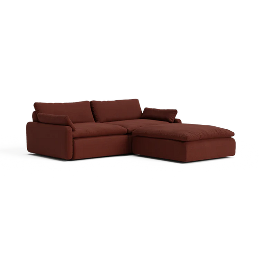 The Sink Down Sectional is a modern, deep burgundy sofa featuring plush cushions and a chaise lounge on the right side, all set against a white background.