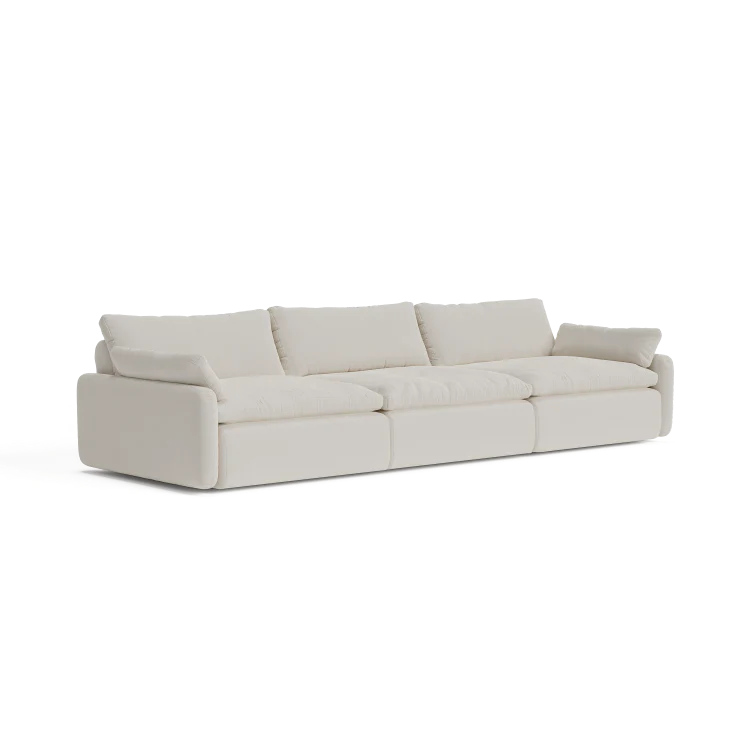 A contemporary, beige three-seater sectional named "The Sink Down Sectional" featuring plush cushions and a minimalist design, set against a white backdrop.