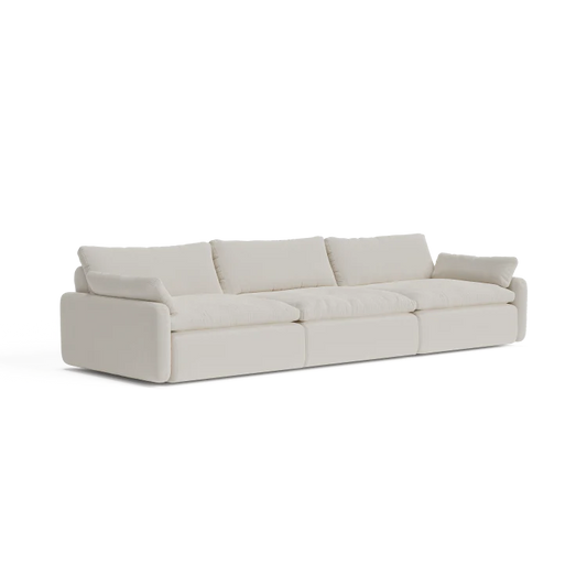 A contemporary, beige three-seater sectional named "The Sink Down Sectional" featuring plush cushions and a minimalist design, set against a white backdrop.