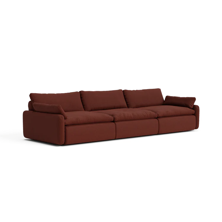 The Sink Down Sectional is a modern and comfortable long, plush brown sofa featuring three seat cushions and four back cushions. It comes with wide armrests and boasts soft fabric upholstery, making it an ideal choice for any living room.