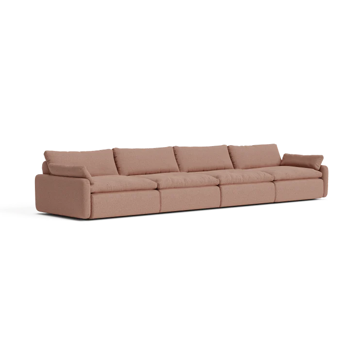 The Sink Down Sectional is a large, light brown sofa with five cushions and low arms on each end, showcasing a minimalist and modern design. Placed against a plain white background, its sleek lines are prominently highlighted.