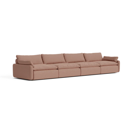 The Sink Down Sectional is a large, light brown sofa with five cushions and low arms on each end, showcasing a minimalist and modern design. Placed against a plain white background, its sleek lines are prominently highlighted.