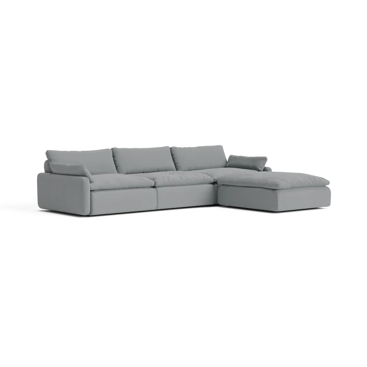 The Sink Down Sectional is a gray sofa with three seat cushions and a chaise lounge on the right side. It showcases a modern design with clean lines and plush back cushions, all set against a white background.