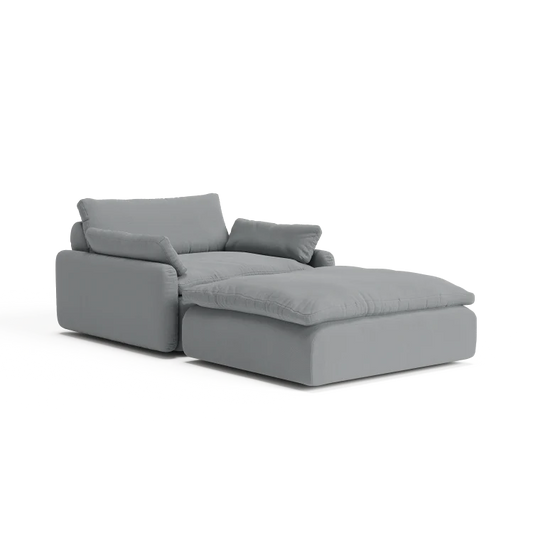 Introducing The Sink Down Sectional, a contemporary gray sectional perfectly paired with an ottoman, showcasing plush cushioning and a sleek, minimalist design against a pristine white backdrop.