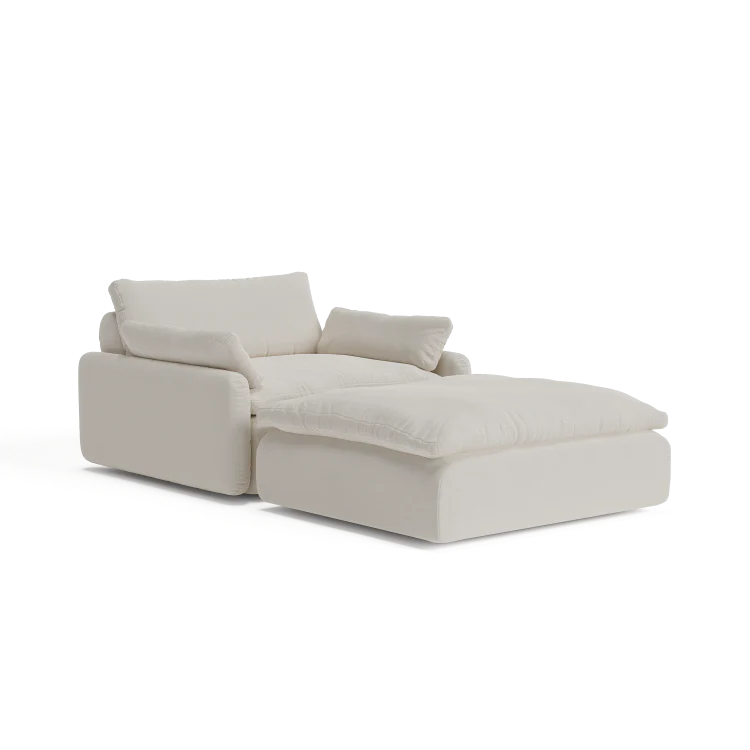 Introducing The Sink Down Sectional: an inviting, off-white chaise lounge featuring thick cushions and a contemporary design with an elevated headrest and armrest on one side, perfect for creating a plush seating area.