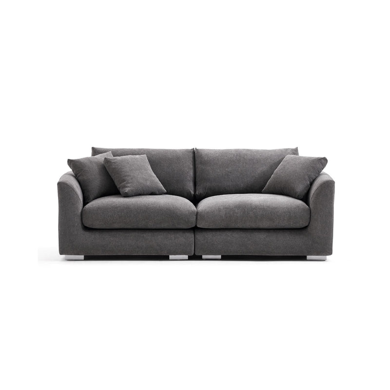 The Feathers 3-Seater Sofa is a contemporary piece in dark gray, offering plush seating and backrest cushions. It boasts a sleek design, complete with two matching throw pillows, and rests on a straightforward metal base against a plain white background.