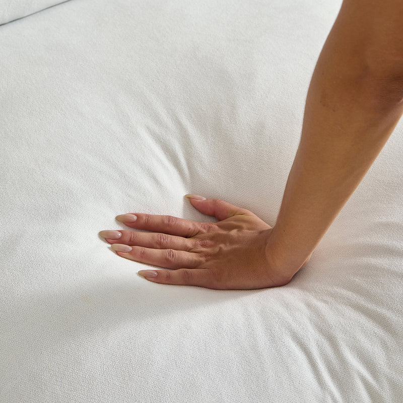 A close-up image of a hand pressing down on the Feathers 3-Seater Sofa showcases its softness and responsiveness, with the person's fingers creating an indentation in the sofa's surface.