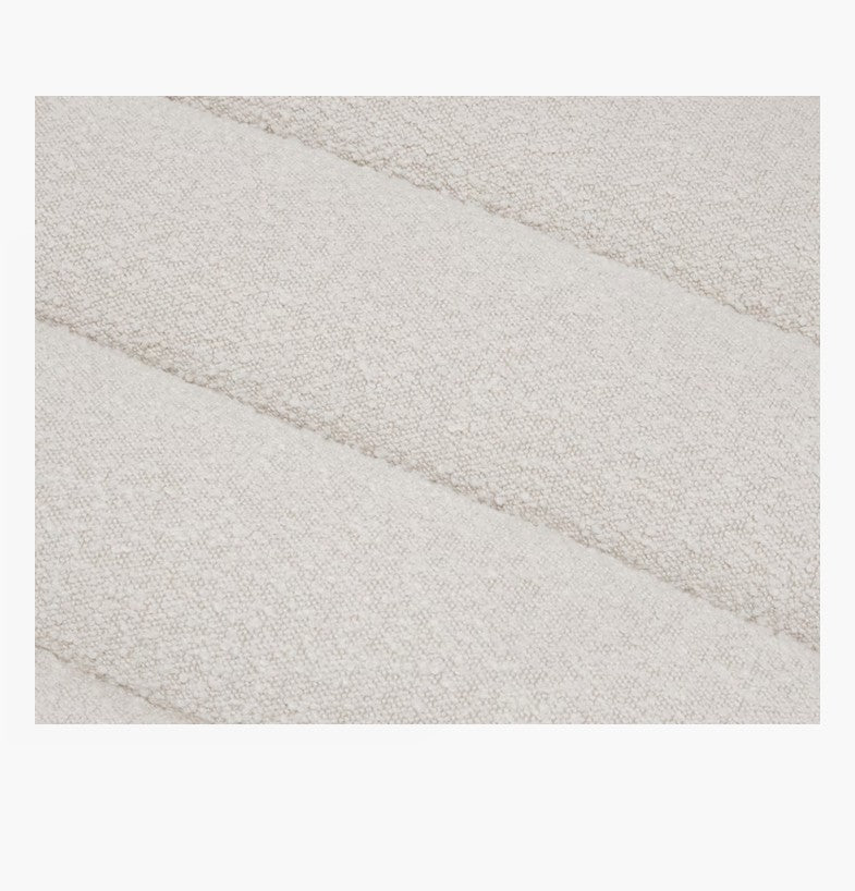 Close-up of the Float Sofa's textured fabric with a soft, off-white color, featuring a subtle pattern of horizontal, puffy stripes.