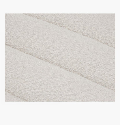 Close-up of the Float Sofa's textured fabric with a soft, off-white color, featuring a subtle pattern of horizontal, puffy stripes.